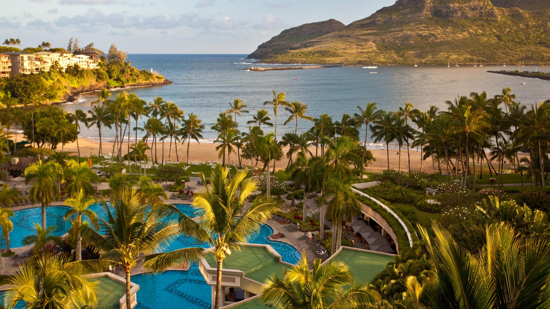 A tropical bay resort with pools and palms beside the sea